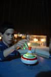 Child playing dreidel during the Hanukkah holiday by the menorah lit