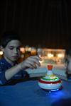 Child playing dreidel during the Hanukkah holiday by the menorah lit