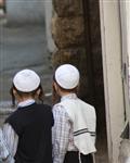 ילדים חסידים עם כיפות לבנות הולכים בסמטא במאה שערים בירושלים