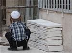 ילד חסידי עם כיפה לבנה יושב בסמטה במאה שערים בירושלים