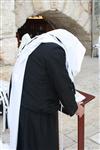 יהודי מתפלל נשען על סטנדר בכותל המערבי