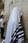 יהודי עטור בטלית מתפלל בכותל המערבי