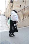 Child being led a prayer shawl towards income study cheder