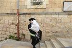 Child being led a prayer shawl towards income study cheder